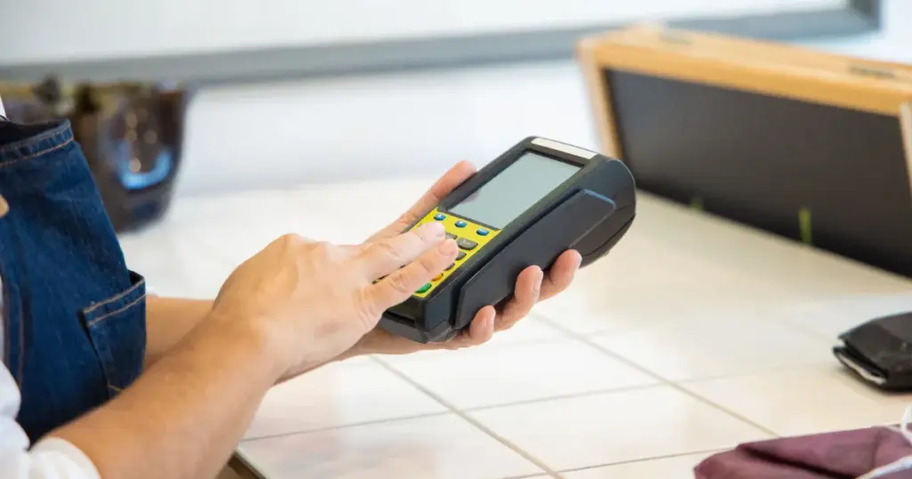 Manos usando una máquina de punto de venta en una tienda
