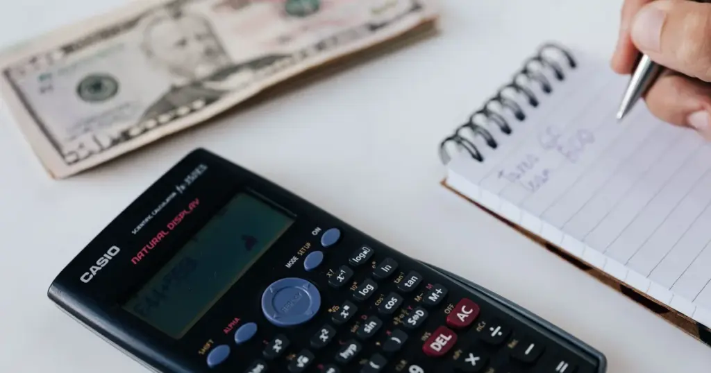 Persona calculando presupuesto en libreta con calculadora