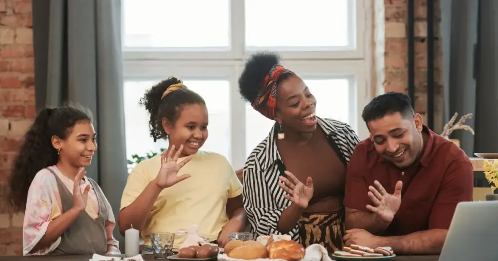 Familia feliz saludando durante una videollamada