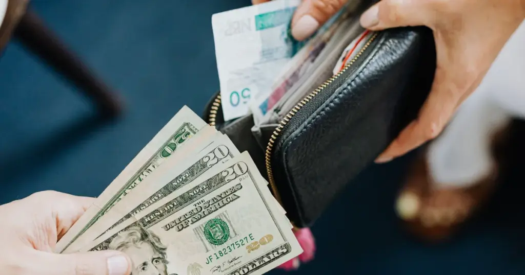 Manos intercambiando billetes de distintas divisas