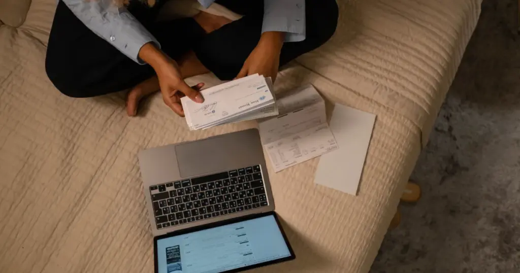 Mujer organizando sus pagos con laptop y comprobantes