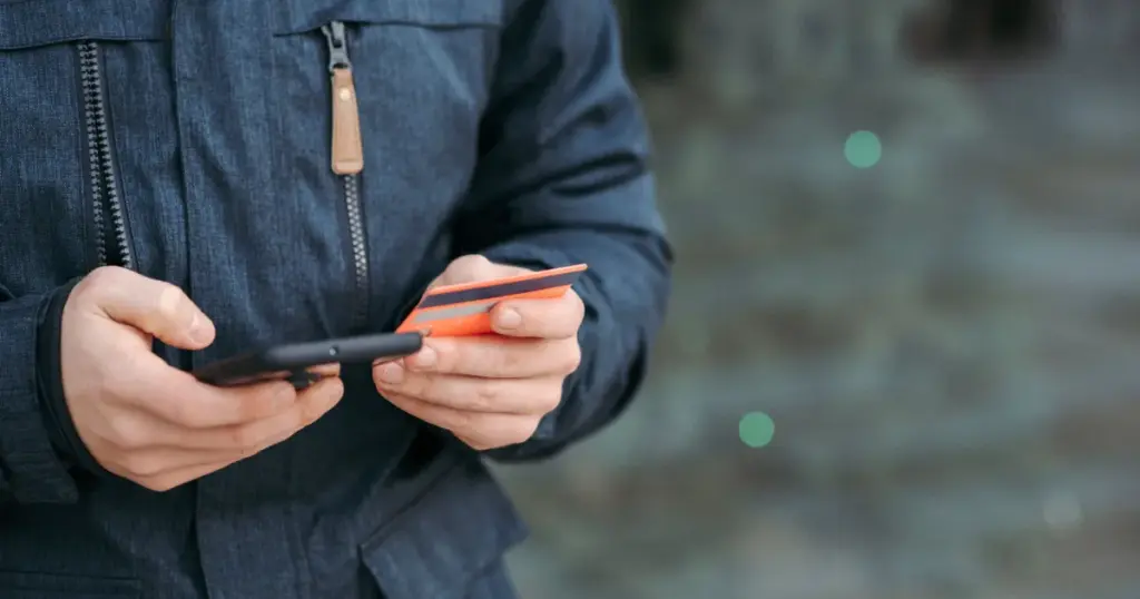 Hombre pagando con tarjeta desde el teléfono en la calle