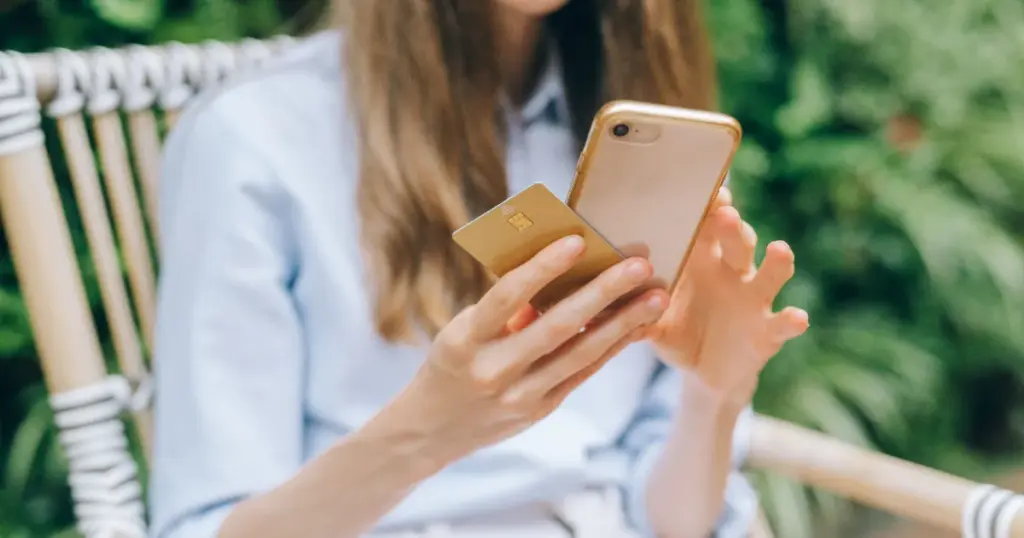 Mujer haciendo un pago móvil con el celular al aire libre