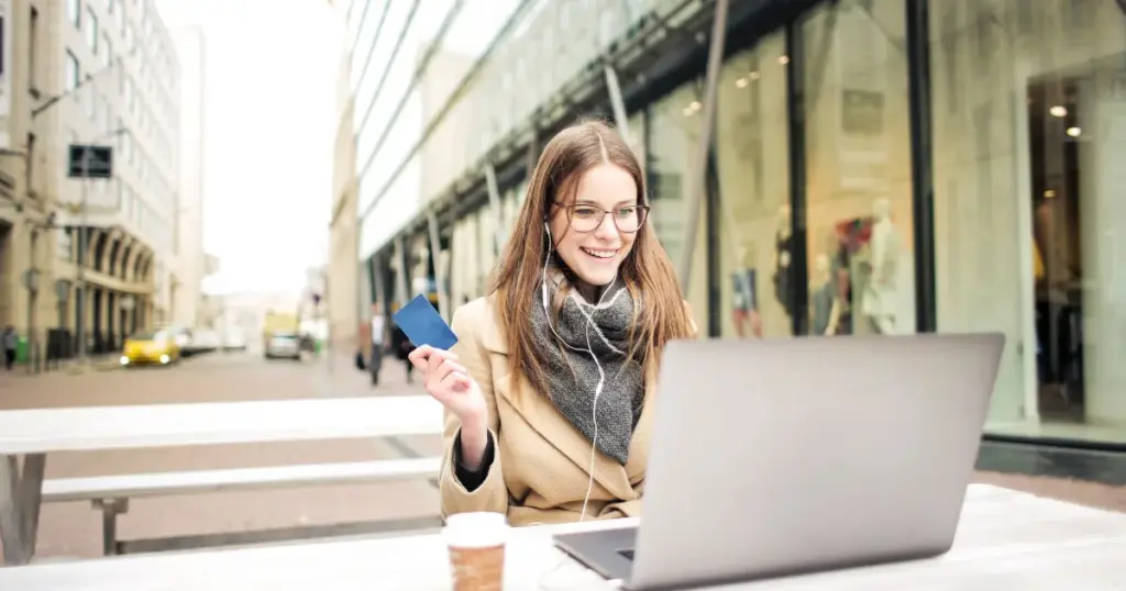 Mujer sonriente usando su tarjeta de crédito de forma responsable con su laptop