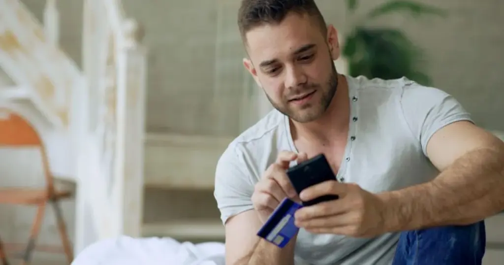 Hombre pagando compra online con tarjeta y teléfono